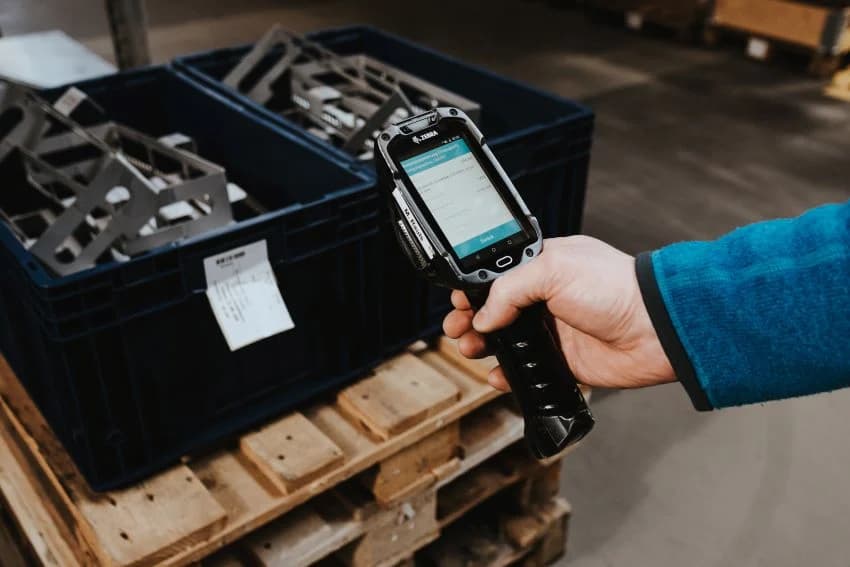 Warehouse worker scans inventory bin using a handheld Android device running an SAP logistics app, part of MKN’s mobile solution for improved inventory control and Kanban management.