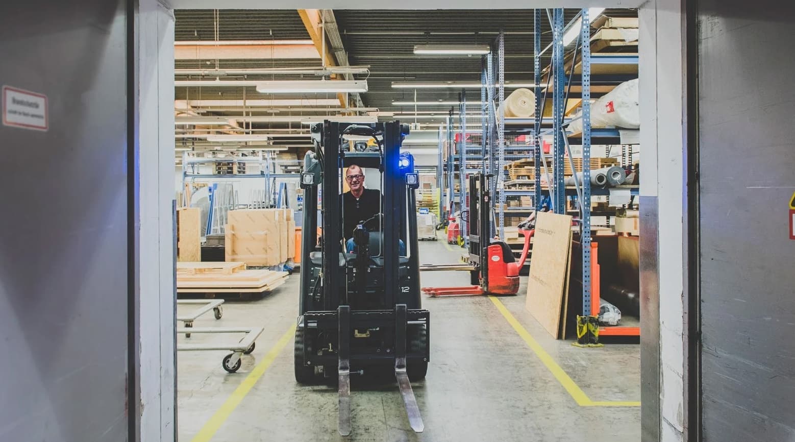 Forklift operator navigating through a warehouse—highlighting real-world intralogistics environments where SAP Fiori’s performance and device integration challenges limit its suitability for barcode scanning on handheld devices.